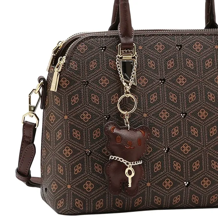 Close da bolsa Chenson café com detalhes em cristais e chaveiro ursinho